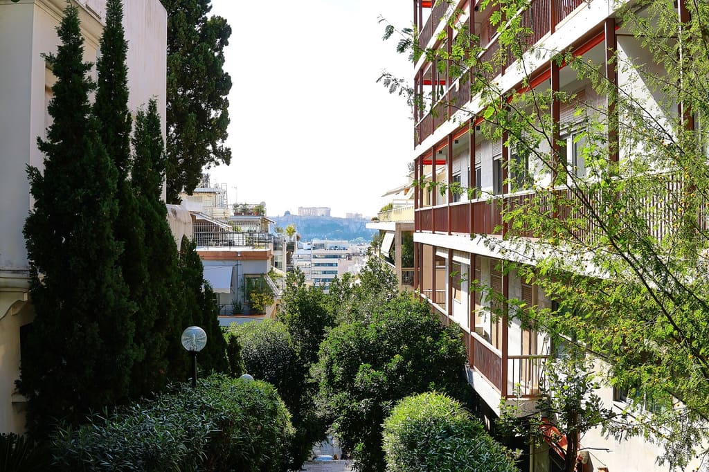 Quiet leafy street in Kolonaki with cypress trees and the Acropolis in the distance